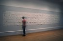 A woman standing at a wall covered in drawings on white paper